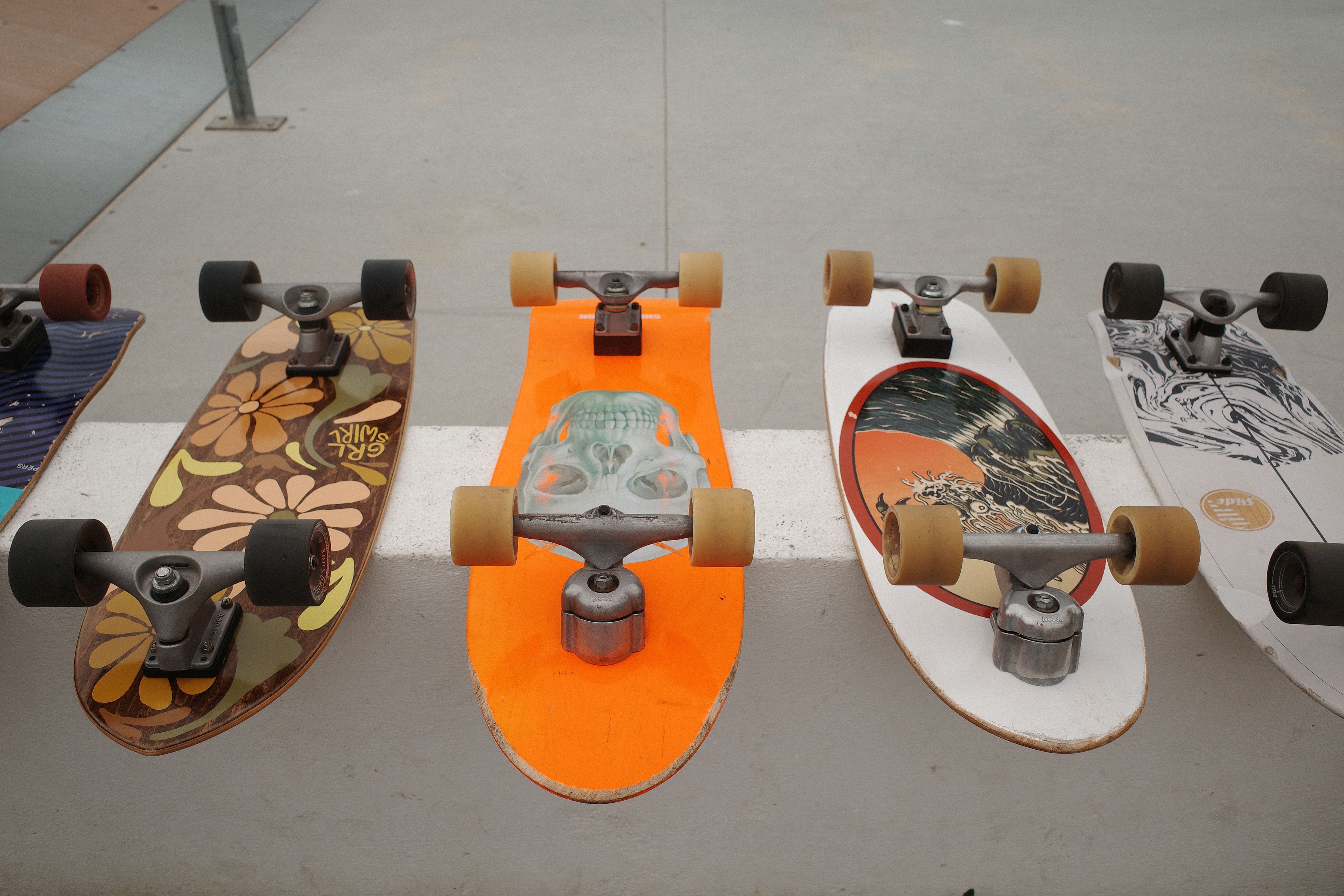 Surfskateboards for rent, all next to each other, showing their beautiful designs.