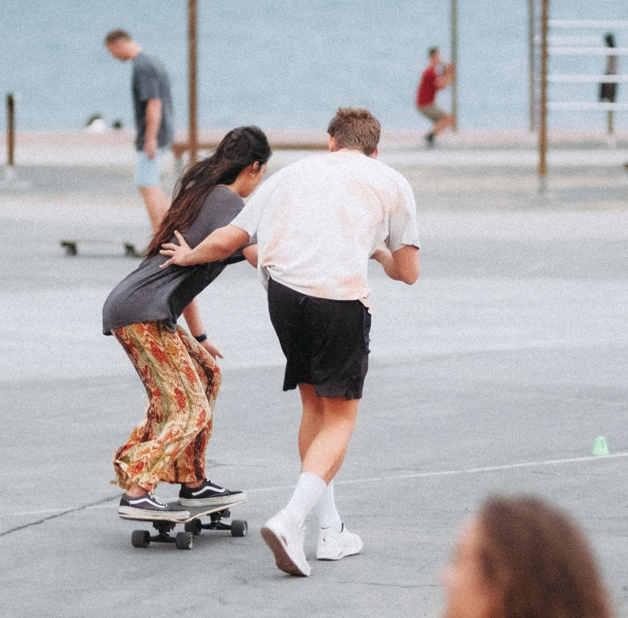A surfskate teacher, teaching a surfskate beginner how to skate.