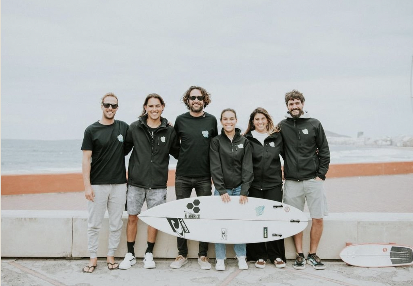 Buensurf school team picture with a surfboard in front of la cicer.